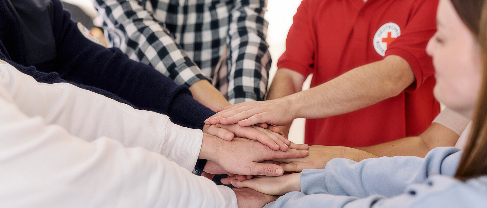 Symbolfoto Solidarität, Mitarbeitende vom DRK legen ihre Hände übereinander