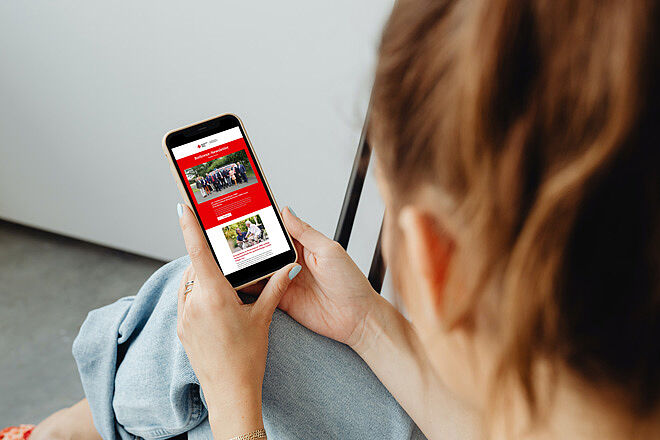 Frau liest auf ihrem Smartphone den Rotkreuz-Newsletter