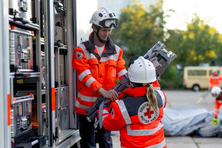 Zwei Ehrenamtlichein Einsatzkleidung des DRK arbeiten im Einsatz eng zusammen.